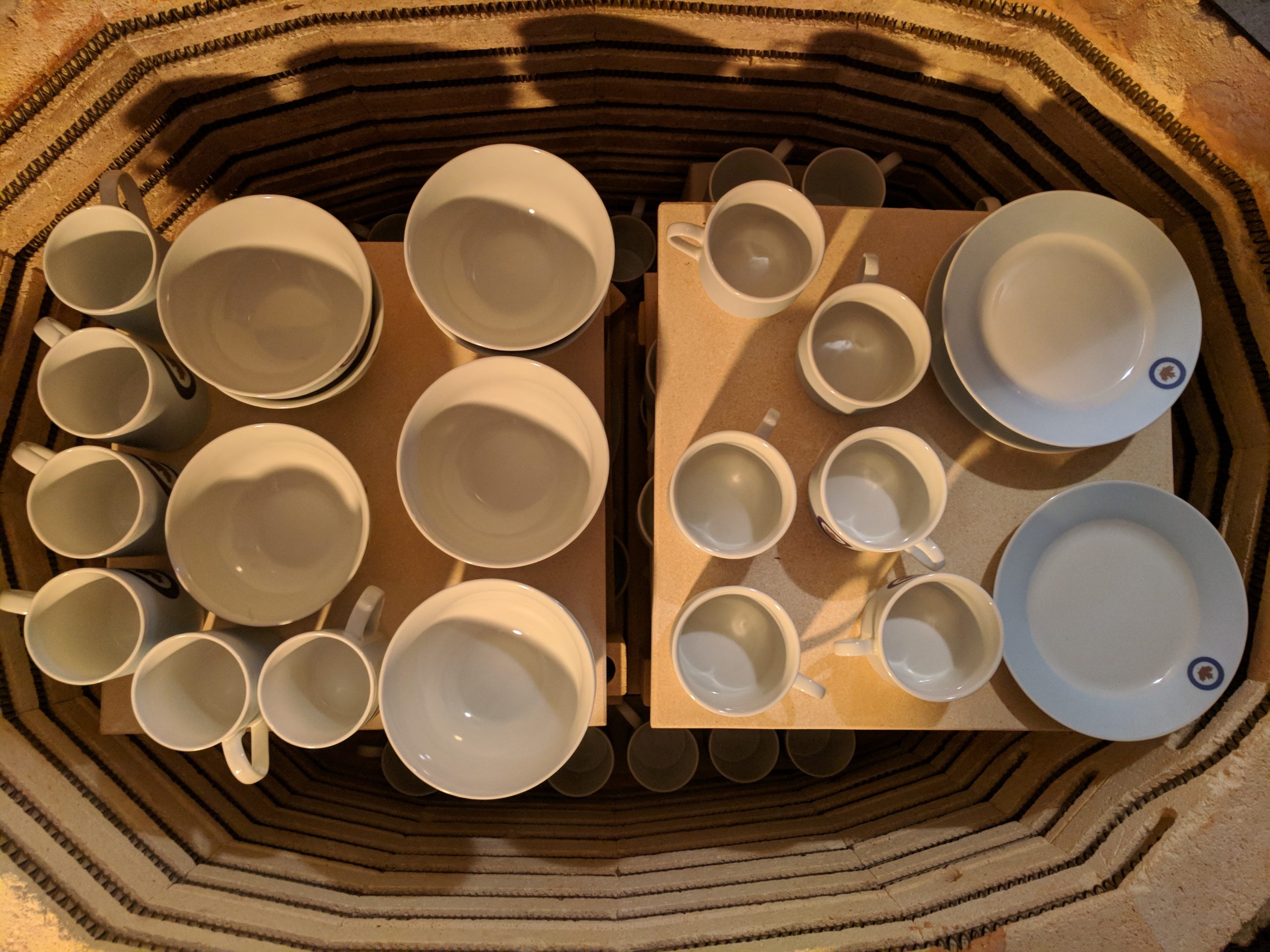 Large kiln loaded with custom porcelain plates during high-temperature firing process