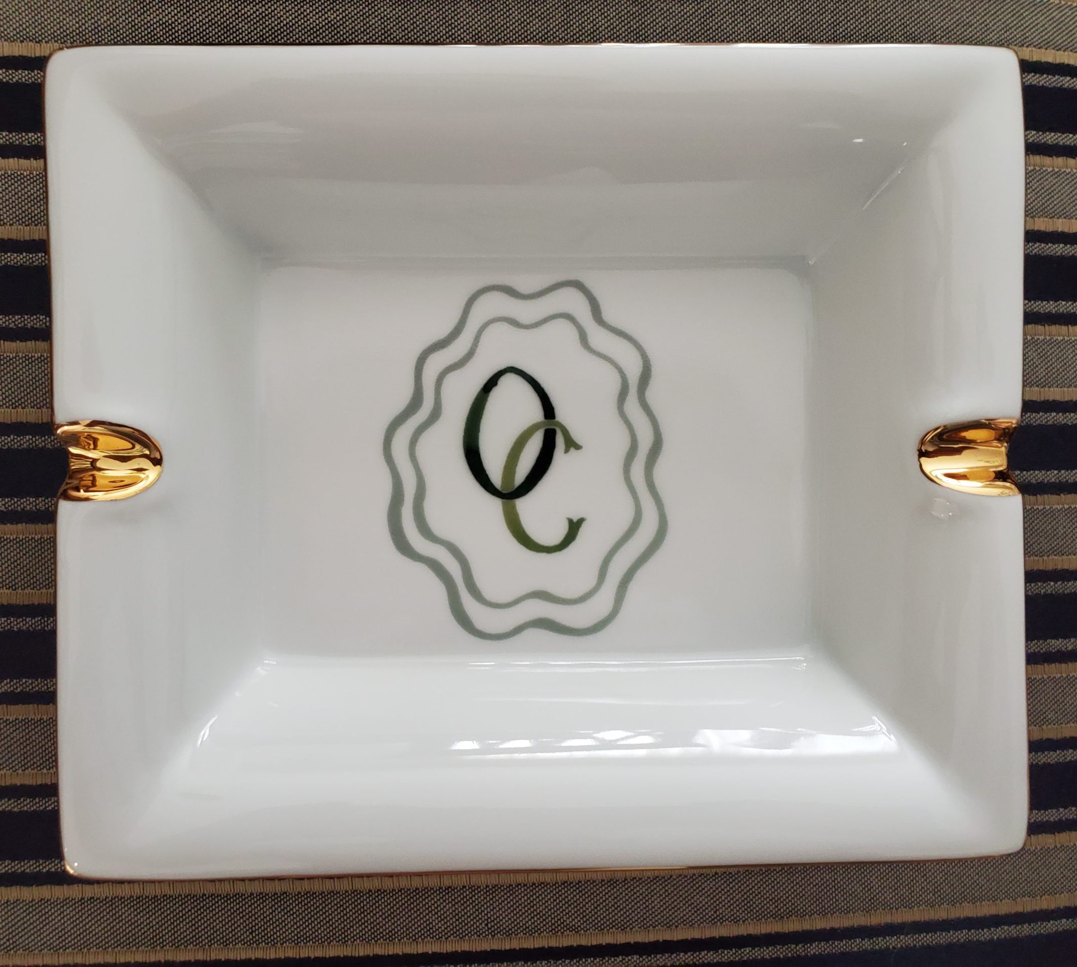Gold rimmed porcelain ashtray custom printed with a monogram logo and crest style artwork
